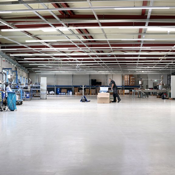 The picture shows a large industrial hall, with machines and equipment to the right and left. 