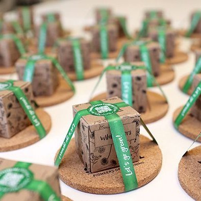 The picture shows lots of little brown mini packets, each on a small cork coaster, wrapped in a green band.