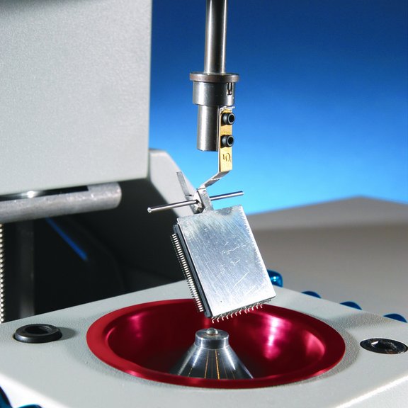 The picture shows a wetting scale. A holder with a component is slowly lowered onto a solder ball.