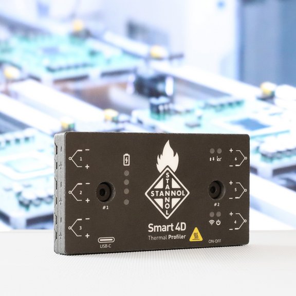 Auf dem Bild ist der Thermal Profiler von Stannol zu sehen, ein rechteckiger schwarzer Kasten mit verschiedenen Ein- und Ausgängen. In der Mitte sieht man das Stannol-Logo. 
