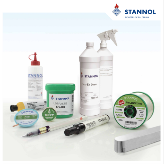 The picture shows various items from the Stannol range, such as a green solder paste tin, a spool of solder wire, a solder bar, a spray bottle of cleaning agent, desoldering braids and flux pens.